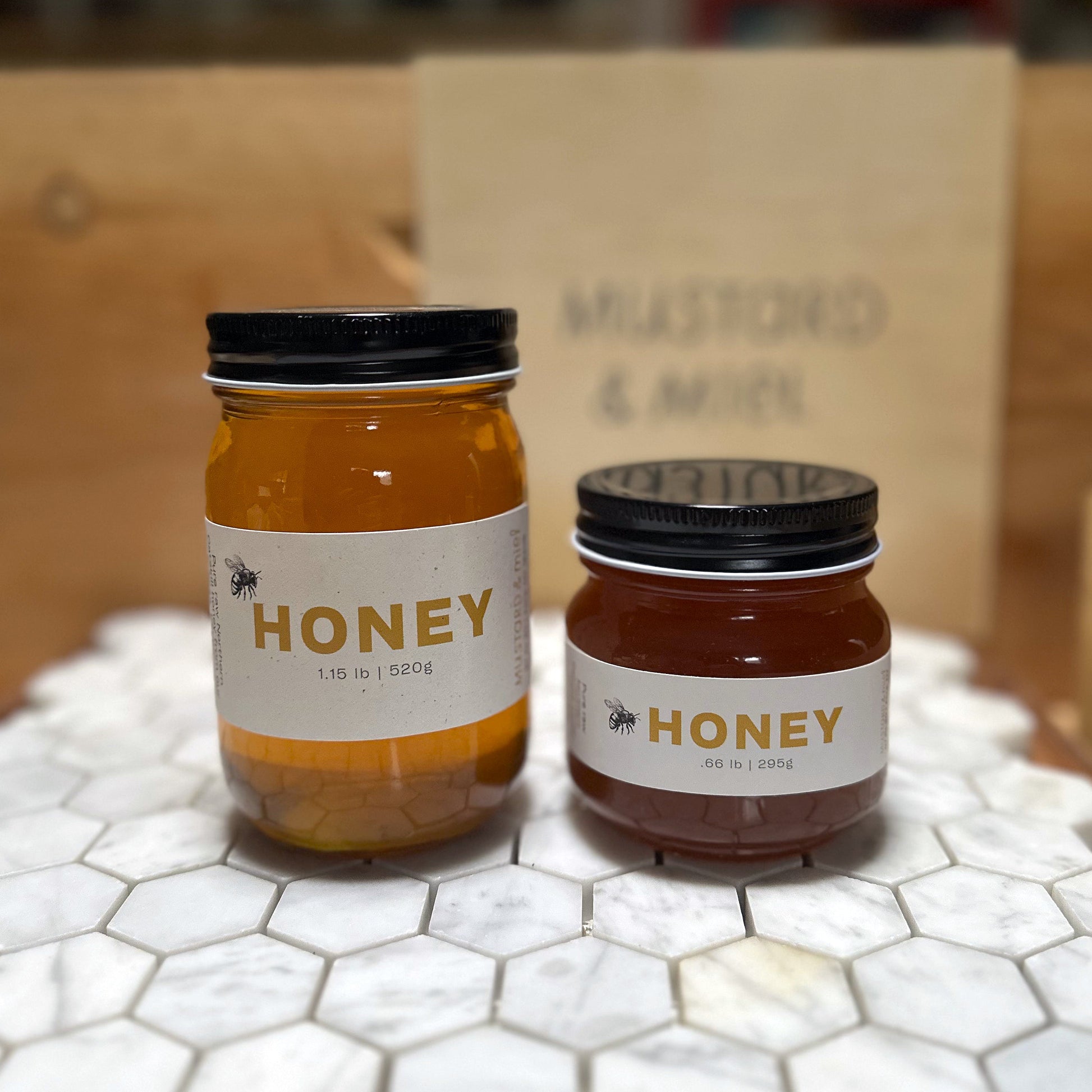 Two jars of honey on a marble surface with a blurred background