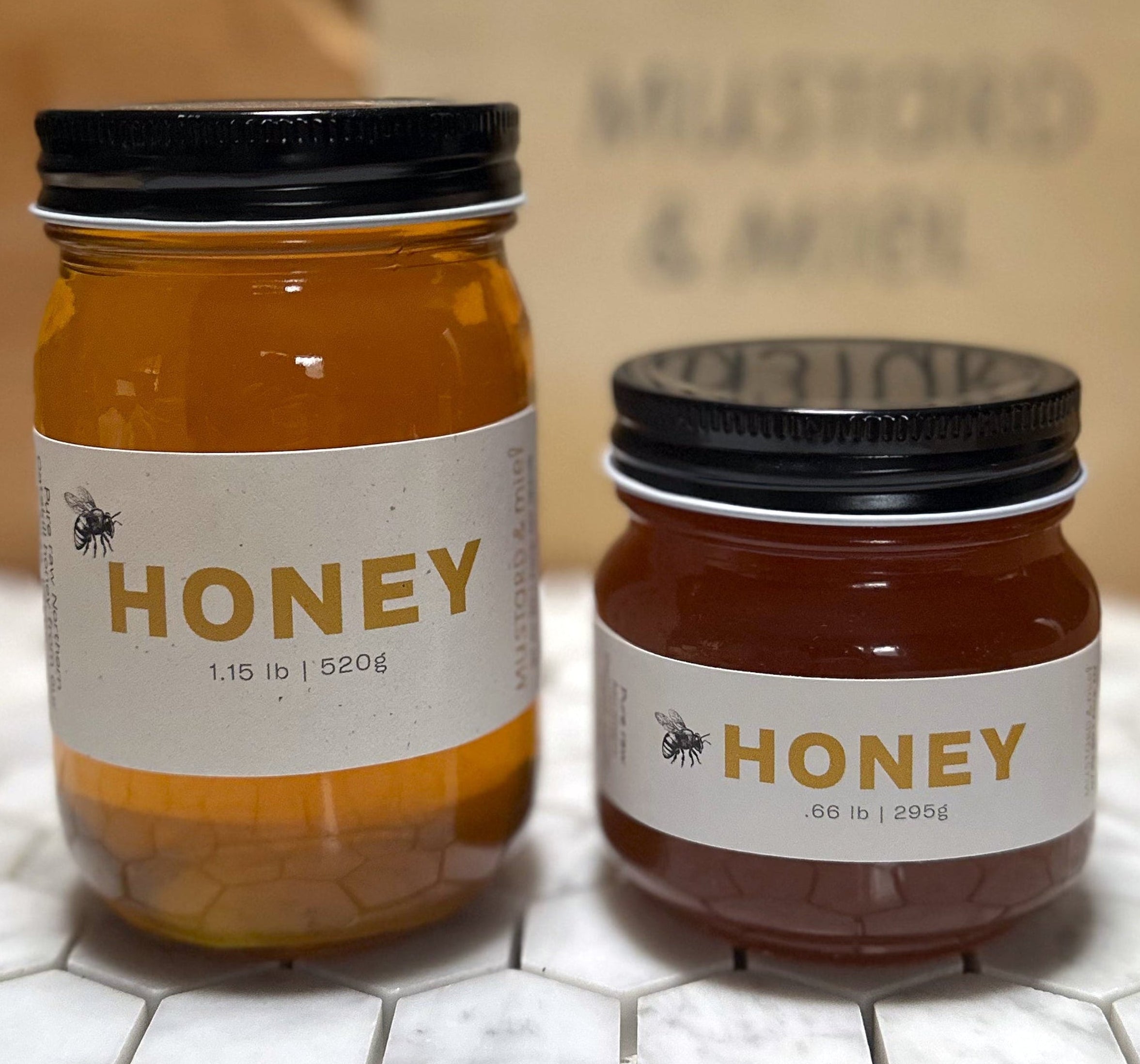 Two jars of honey on a marble surface with a blurred background